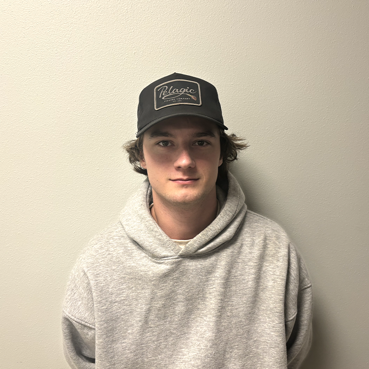 Young man with a grey sweatshirt, dark green cap, and brown hair smiling.